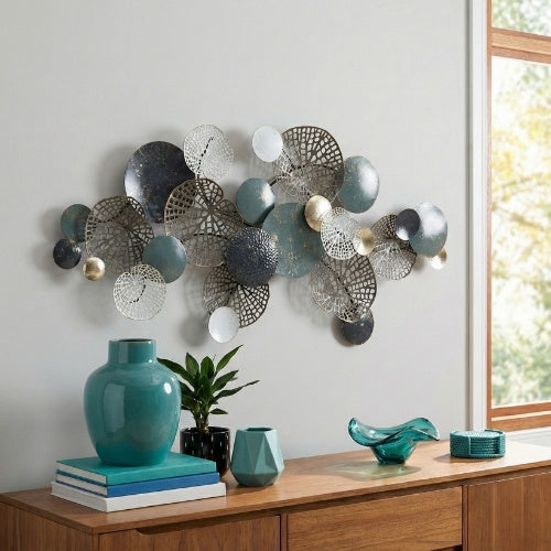 Gemini said Rivercity Furniture's modern metal wall decor, featuring interconnected blue, white, and gold circles and leaf shapes, hangs above a wooden sideboard with teal vases and a plant.